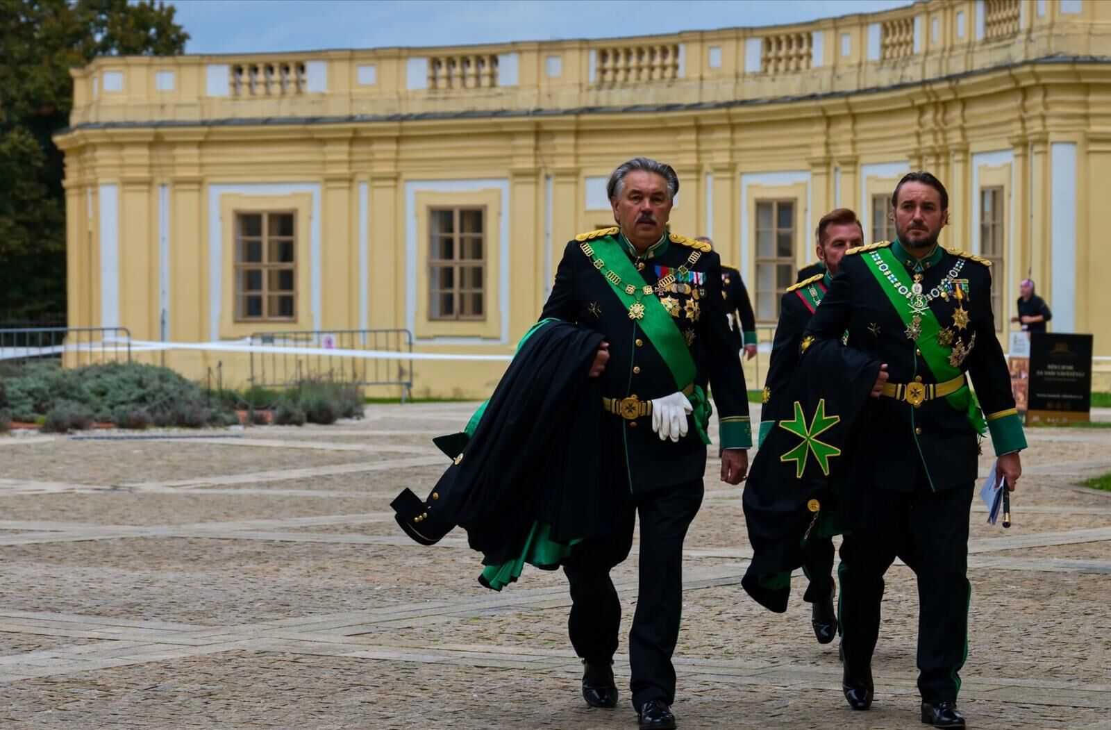 Members of the Order in black mantle in a palace courtyard
